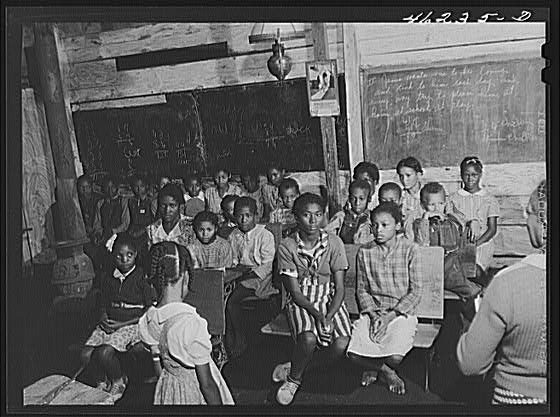 Photograph of a segregated black schoolroom from the 1930s. Conditions are dilapidated and appear to be harsh for the children.